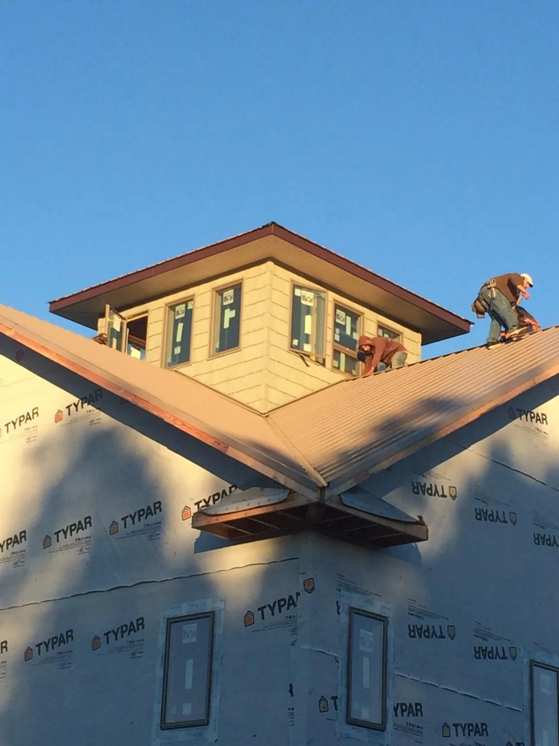 Roofers working around a rooftop cupola on a new metal roof at sunset — Roof Waterproofing in Ocean City by Roofing Brothers